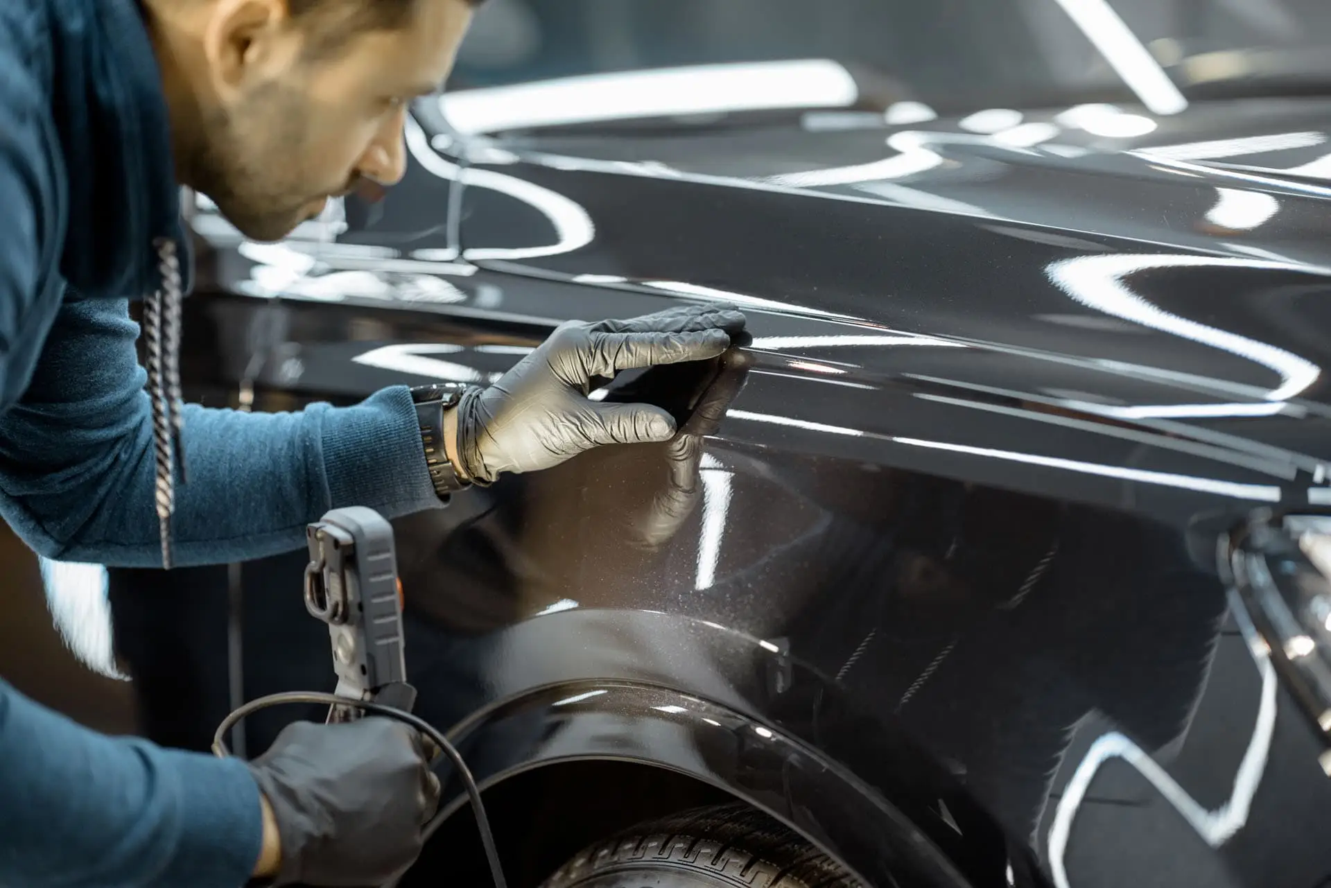 Technician inspecting paint under LED light with a paint thickness gauge, Colorado Springs