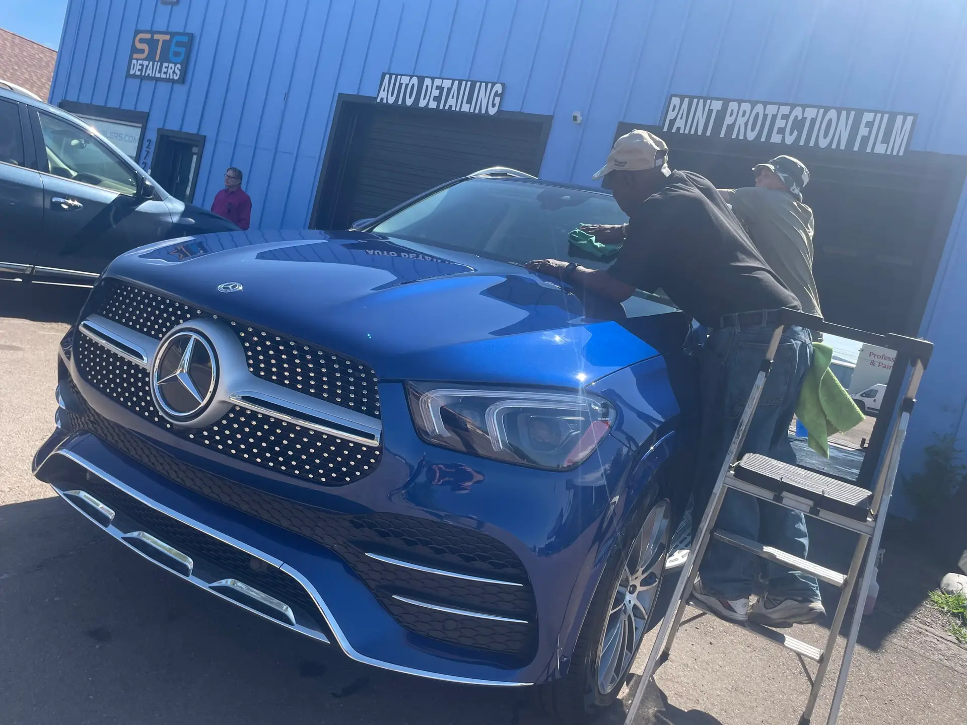 ST6 technicians hand-finishing a vehicle hood after machine polishing